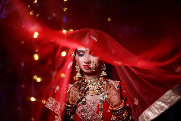 Bride under a red veil lit by warm lights
