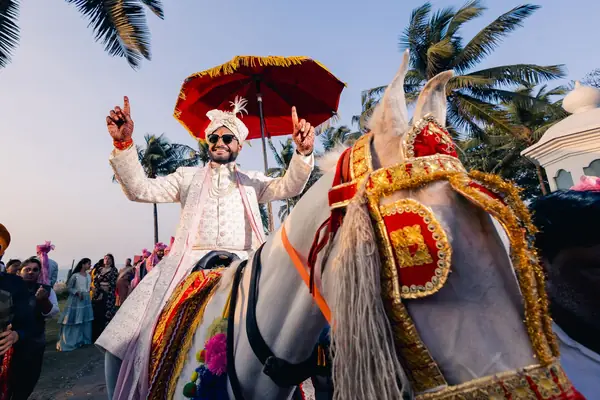 Groom arriving on a horse under a red umbrella
